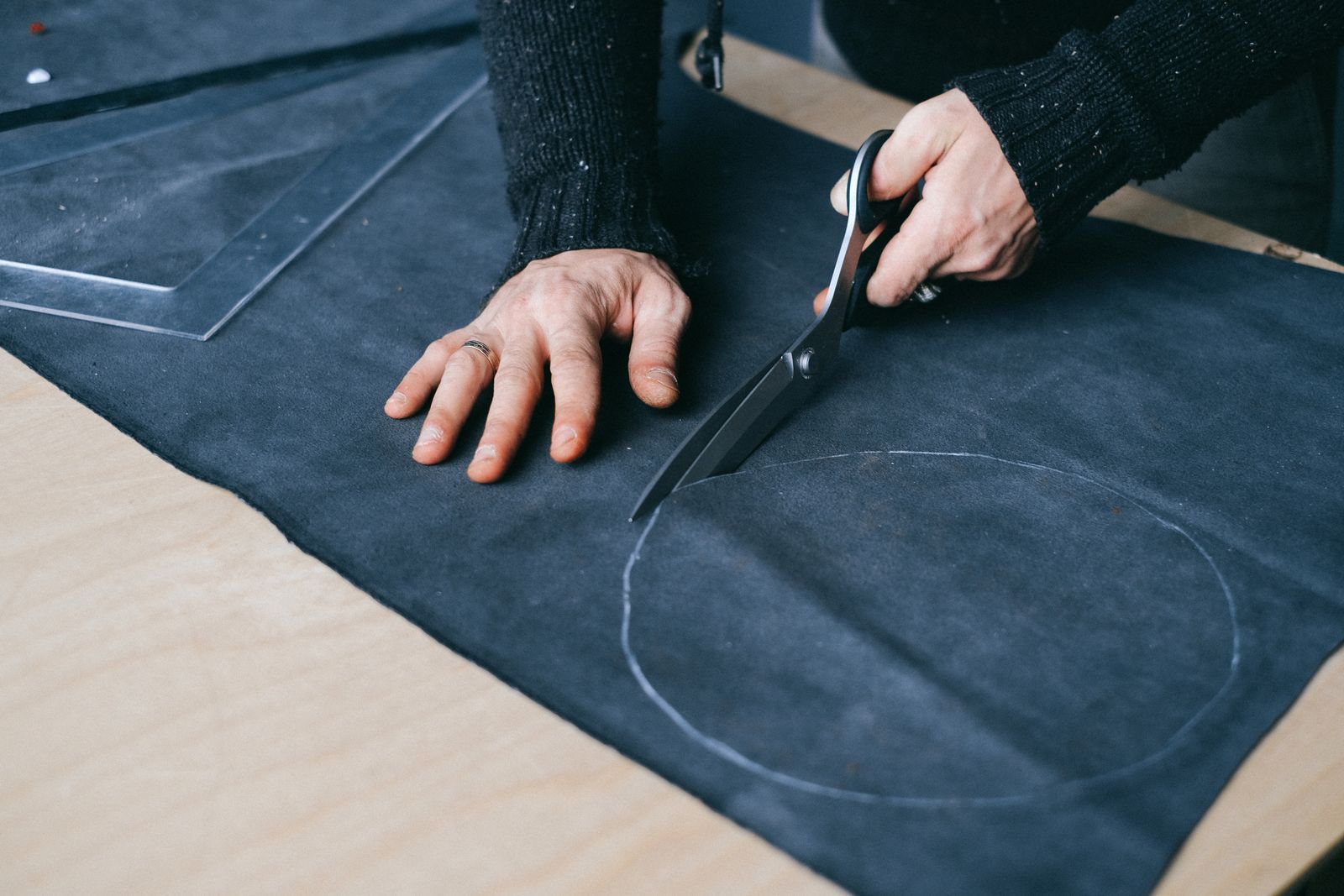 Artisan measuring and cutting material at a workbench